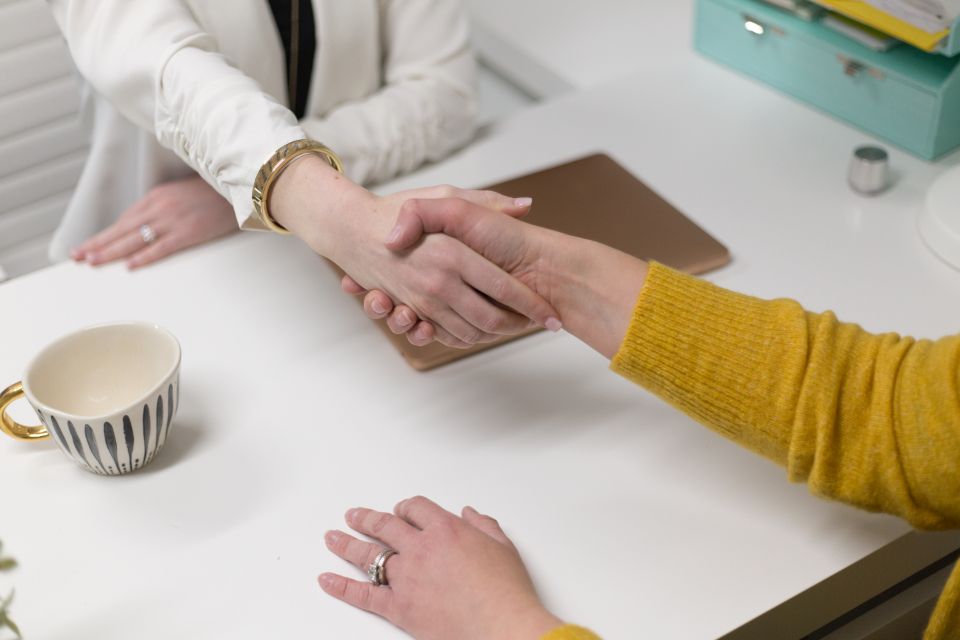 Aperto de mão entre duas pessoas sobre uma mesa de trabalho